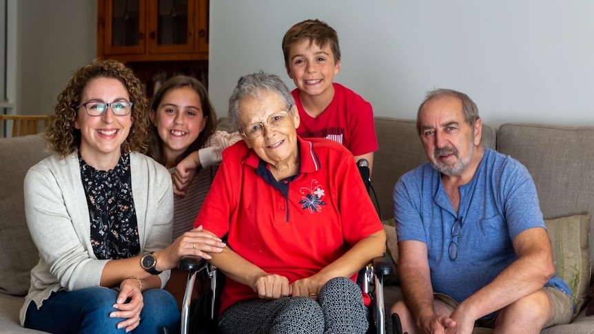 A woman in a wheelchair surrounded by her family.