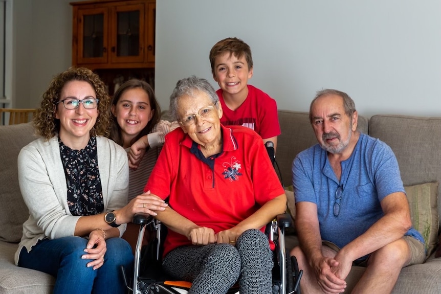 A woman in a wheelchair surrounded by her family.