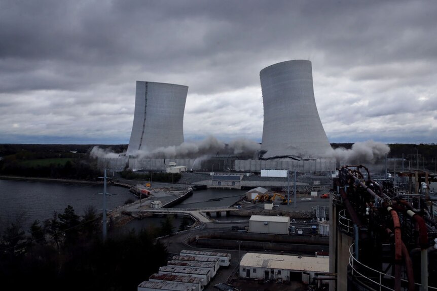 Two cooling towers from a power plant begin to fall.