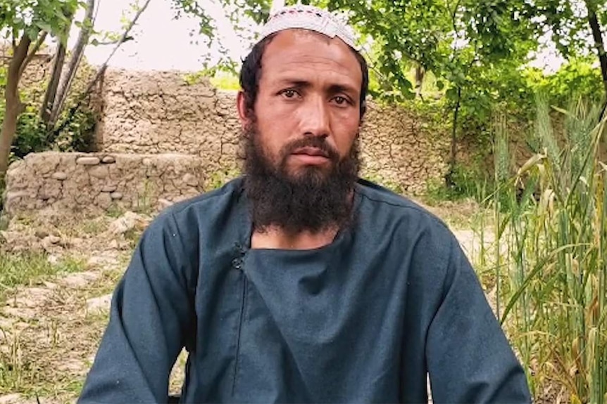 An Afghan man in traditional dress looking concerned down the barrel of the camera.