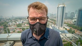Man stands on a Jakarta rooftop with a face mask.