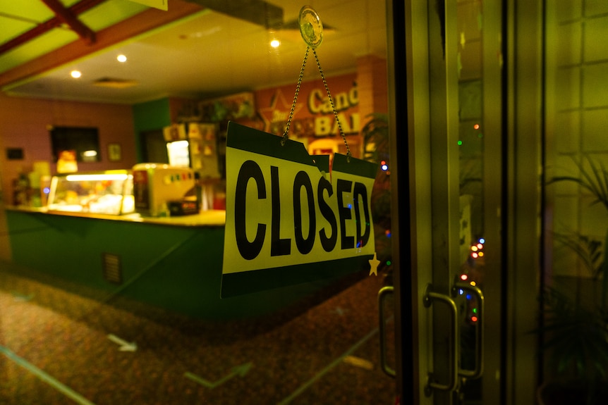 A "closed" sign on a glass door. In the background you can see a movie theatre candy bar.