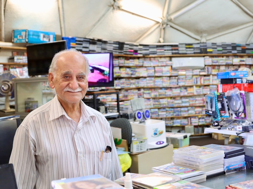 Old man in stripy shirt standing behind the counter