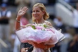 Chris Evert with a bunch of flowers in the hand waves to the crowd at Roland Garros  