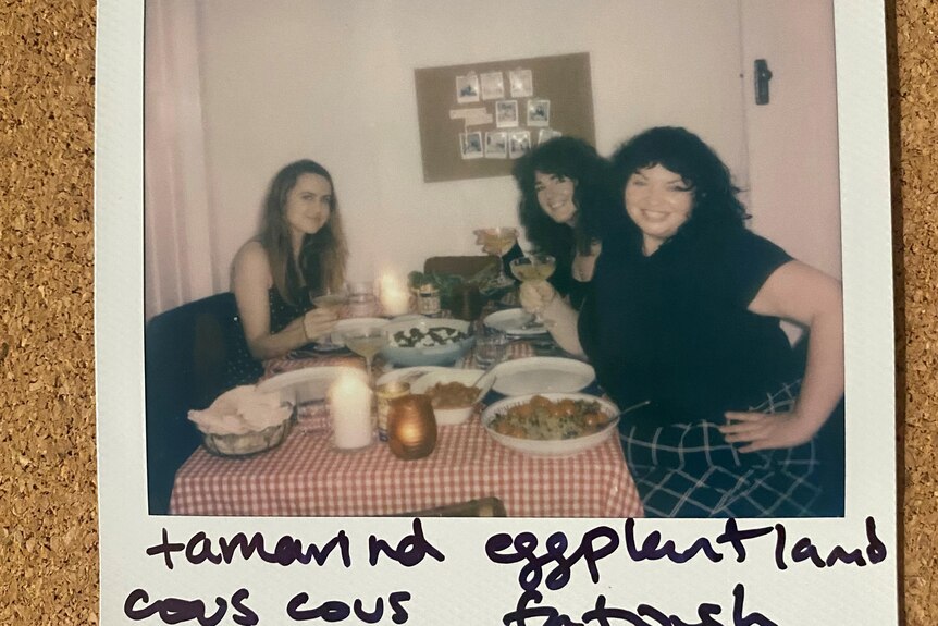 A polaroid of three people having dinner in a restaurant together.