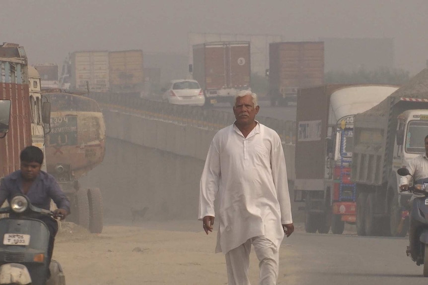 A man walks down a polluted road in New Delhi, India