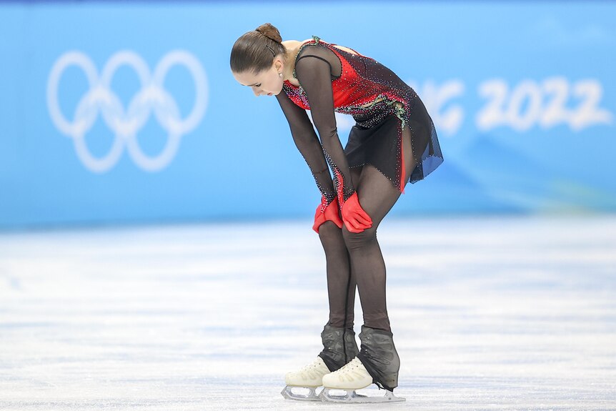 A figure skater looks down at the ice with a disappointed expression