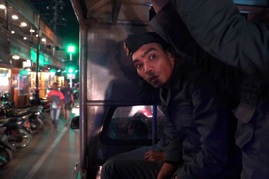 An officer peers out from a travelling vehicle