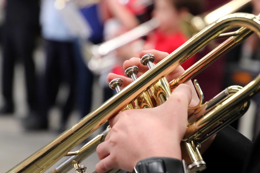 A close-up of hands playing the bugle.
