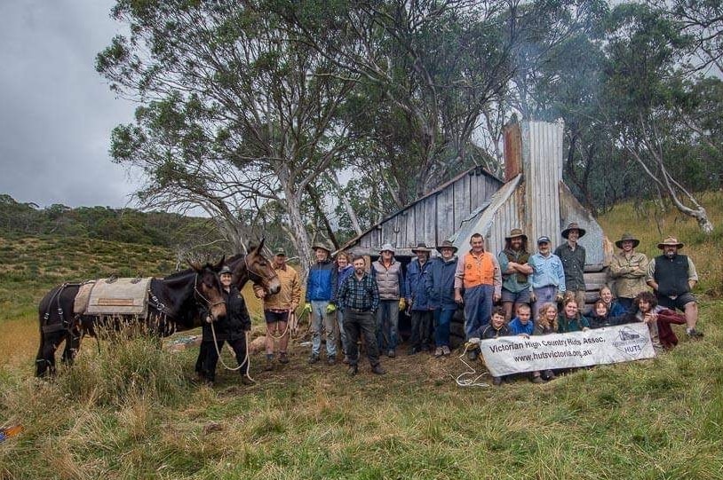 Volunteers and a pack horse stand outside a hut