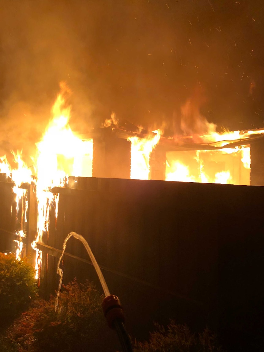 Flames leap from the windows of a house