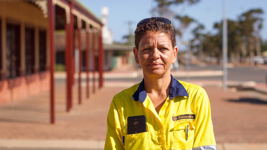 Woman in high vis shirt stands on street