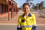 Woman in high vis shirt stands on street