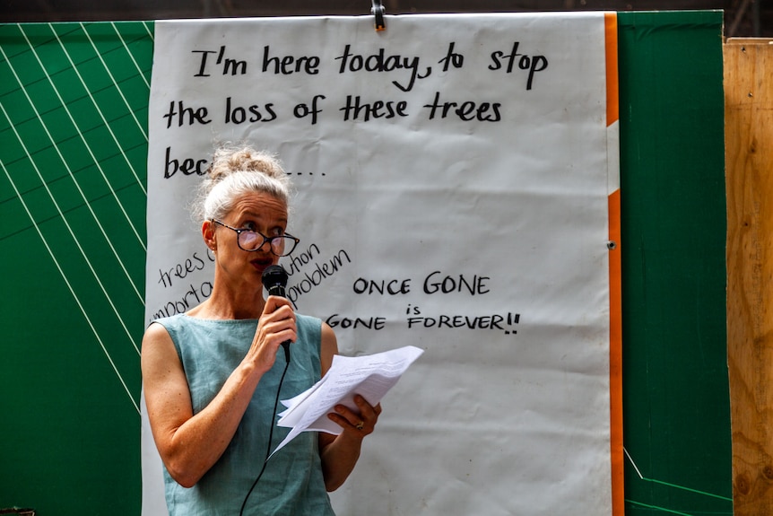 A woman speaking into a microphone in front of a banner