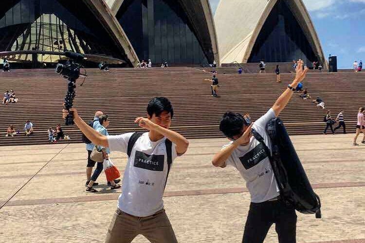 Brett and Eddy with their arms up dabbing outside the Sydney Opera House.