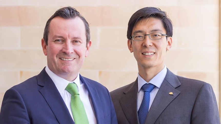 Mid shot of two men in suits smiling at the camera.