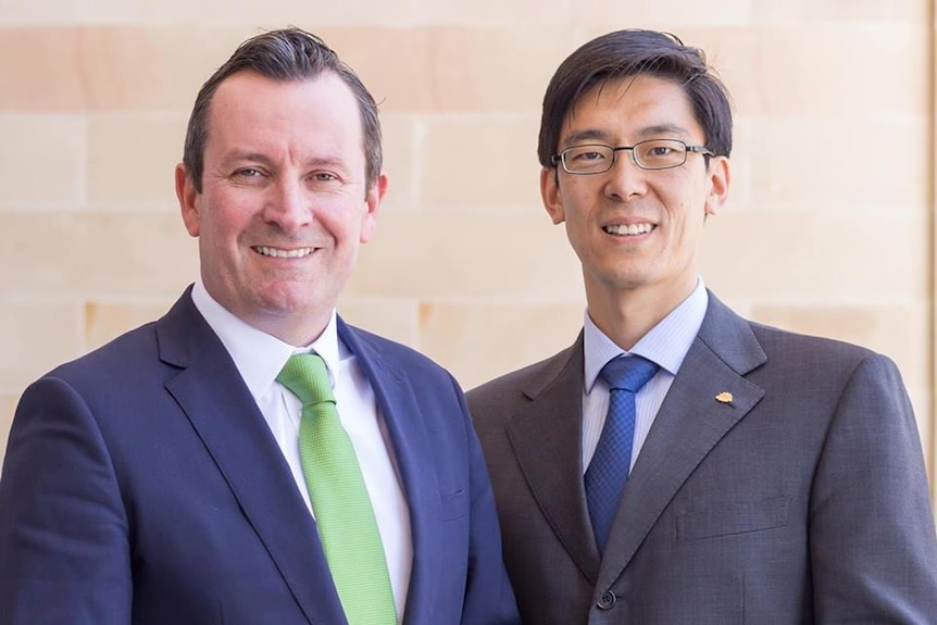 Mid shot of two men in suits smiling at the camera.