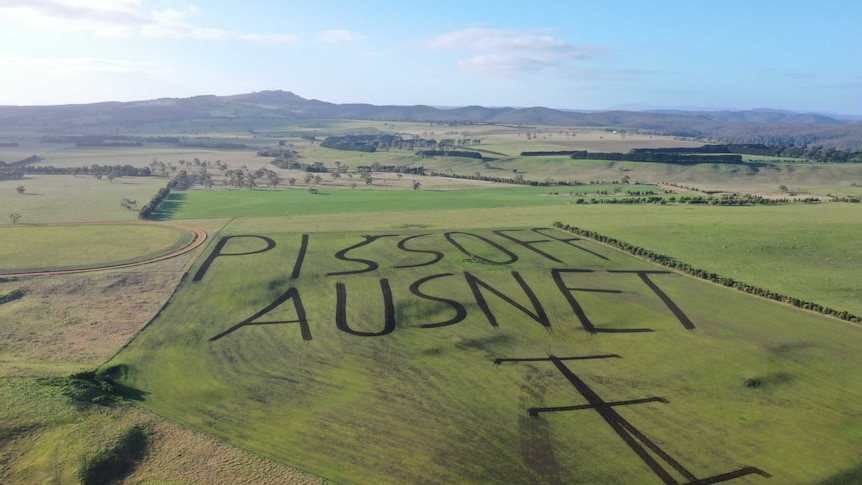 A drone photo of a western Victorian farm with a paddock ploughed to read "piss off Ausnet".