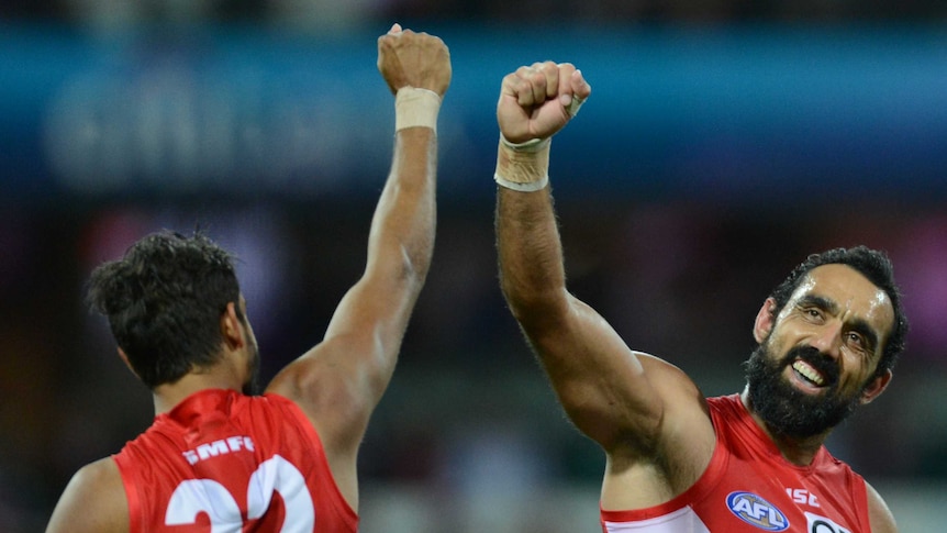 Two players in Sydney Swans red and white guernseys fist bump in celebration.