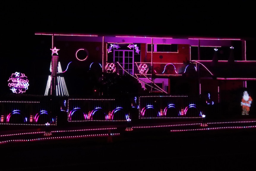 A home is illuminated by strips of pink lights running along the facade.