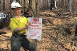 A national park worker attaching a 1080 poison sign to a tree.