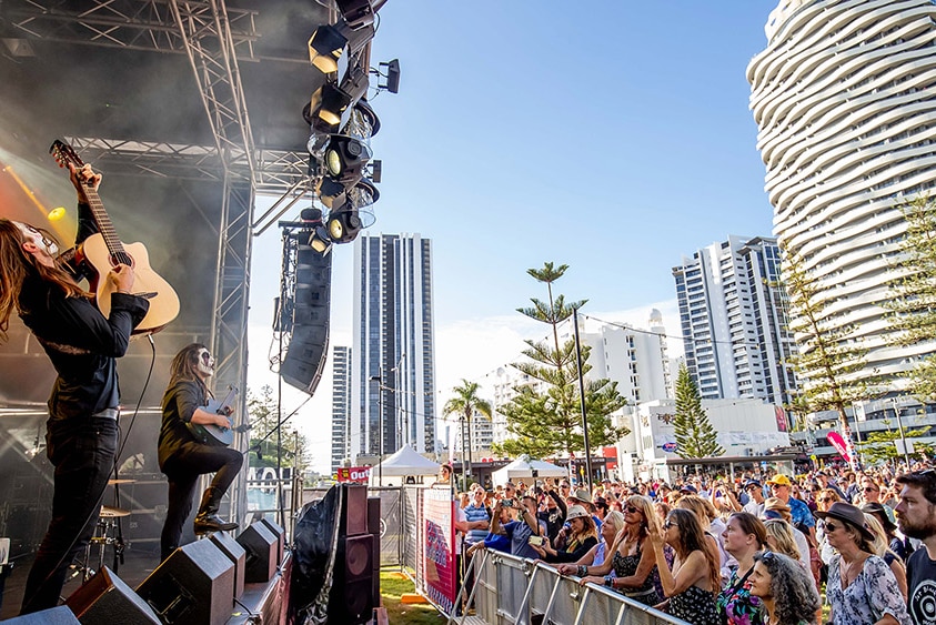 A band performs at Victoria Park in Broadbeach against a backdrop of skyscrapers and pine trees