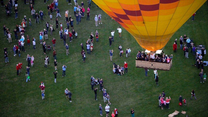 Spectators watch a hot air balloon after take off