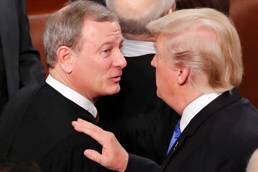 A man in a suit puts his arm on a man in judge's robes