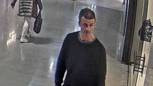A grainy CCTV image of a man with short dark hair and a black jumper.