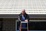 Man standing on ladder in front of white roof.