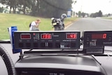 Police radar speed with motorcyclist with head in his hands on the grass outside the police car