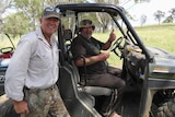 Two men smiling, one of them sitting in a utility terrain vehicle