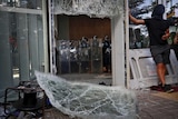 Police inside Hong Kong's Legislative Council stand back after protesters smash through windows.