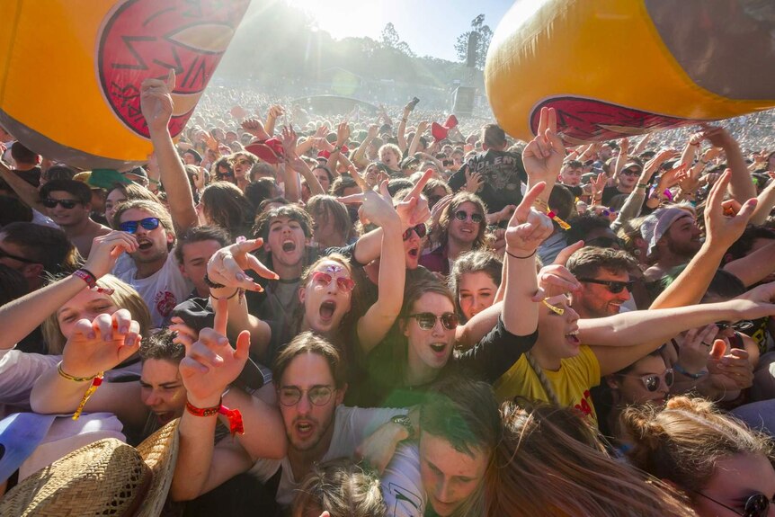 Tightly packed crowd throwing inflatable yellow beer cans around