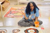 an artist sits above her painting