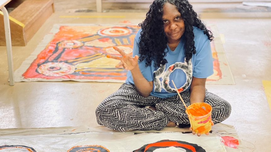 an artist sits above her painting