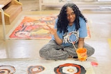 an artist sits above her painting