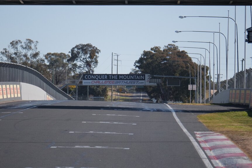 bitumen race track with signs and barriers either side of road 