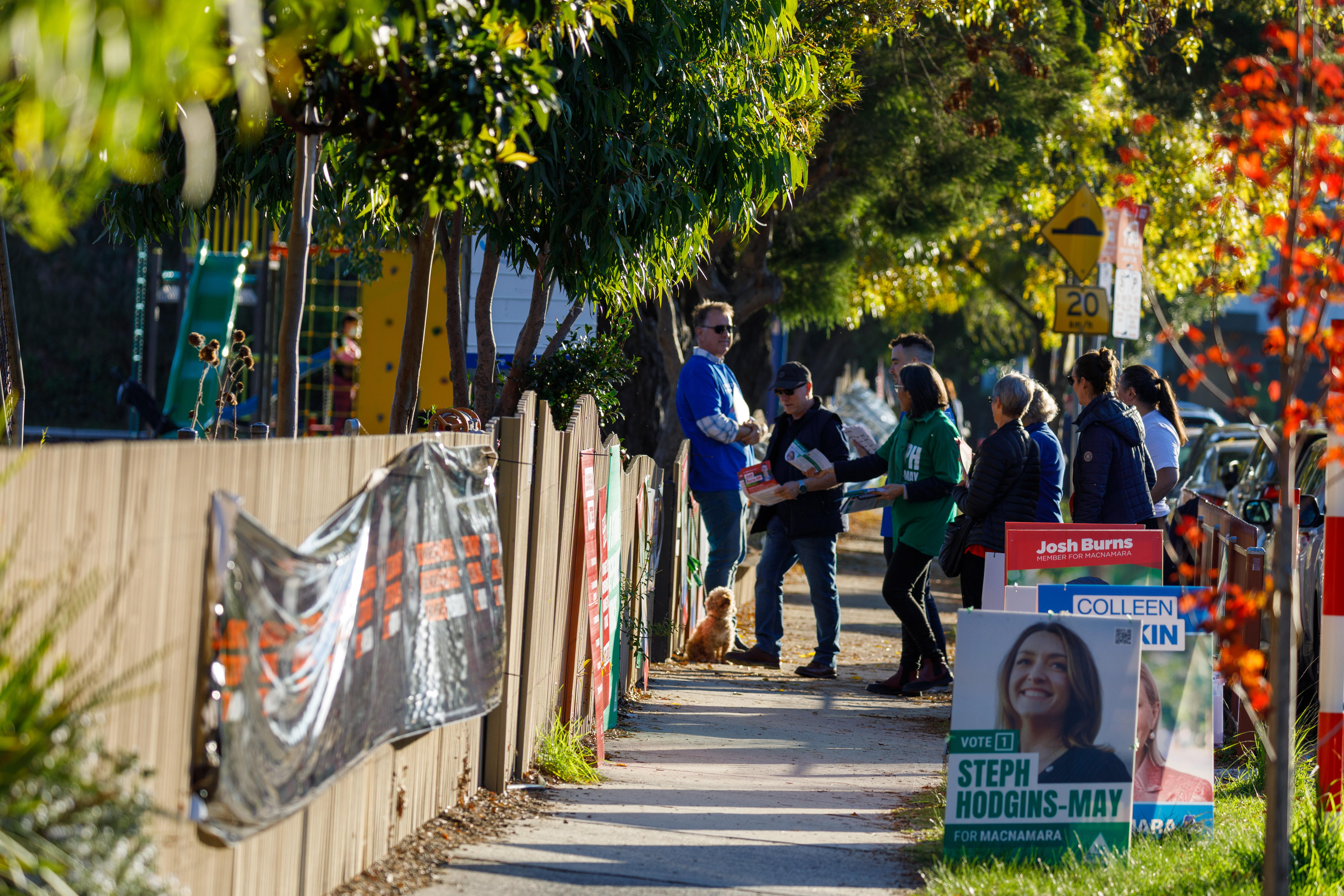 Volunteers hand out how-to-votes at a polling centre. A corflute for Steph Hodgins-May is in the foreground.