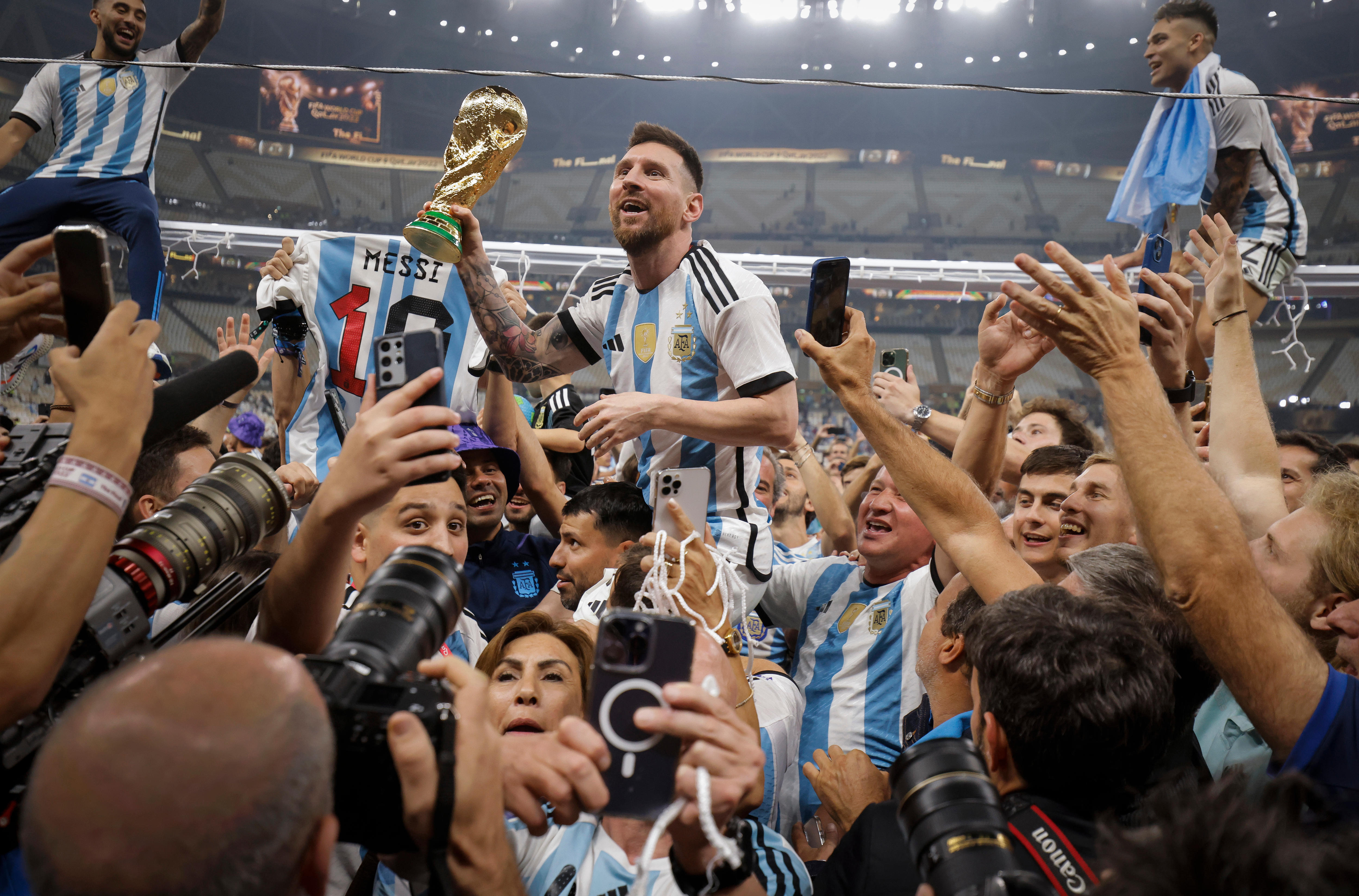 Argentina superstar Lionel Messi grins as he holds the World Cup trophy in the air as he is hoisted on shoulders.