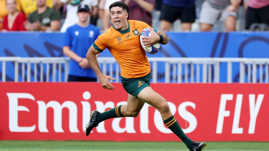 A Wallabies player holds the ball with his left hand as he runs away to score a try at the Rugby World Cup.