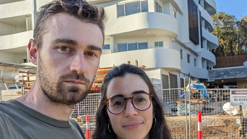 A man and woman standing in front of a unit construction site