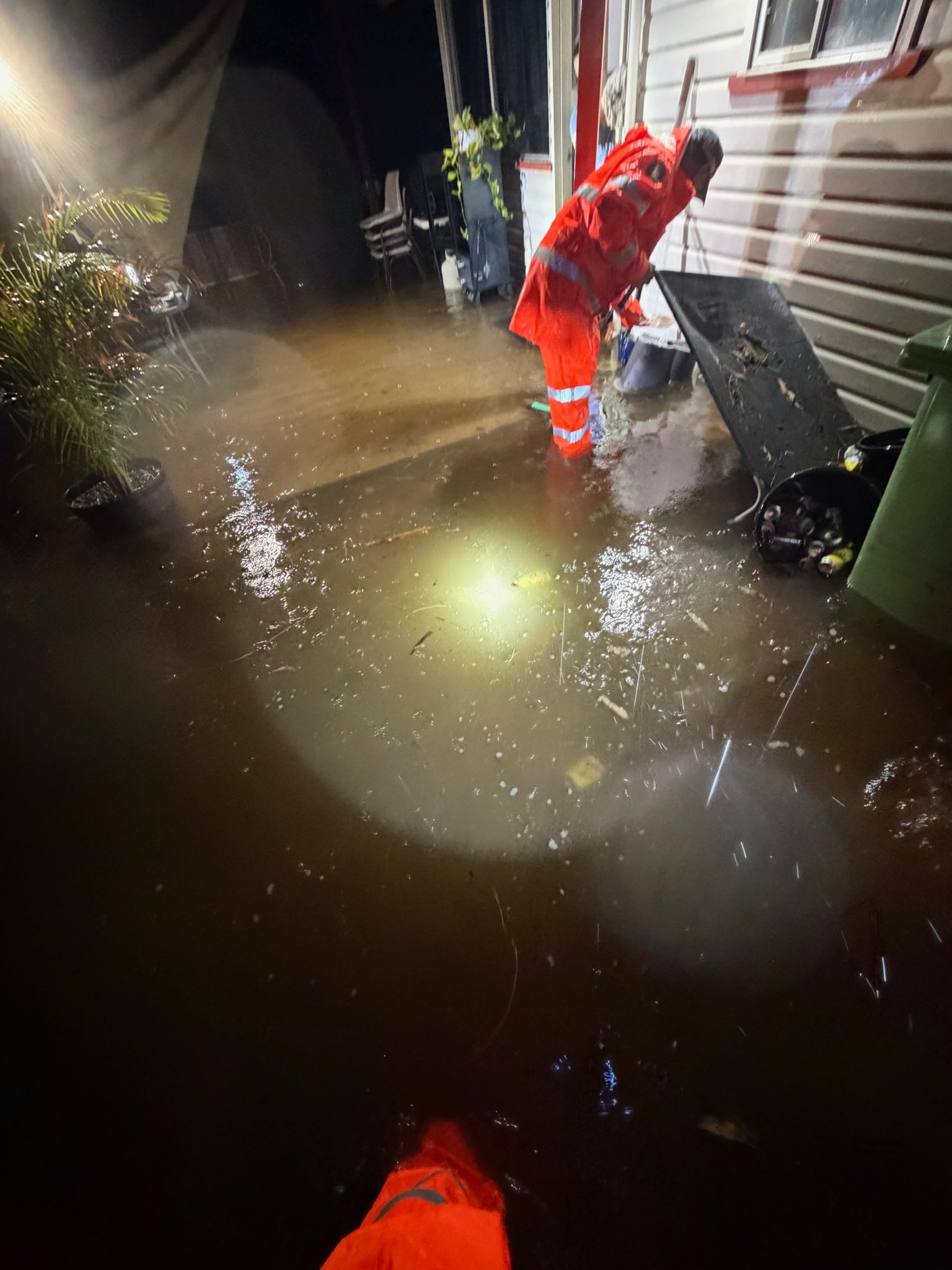 Uma pessoa com um traje de alta visibilidade em águas inundadas.