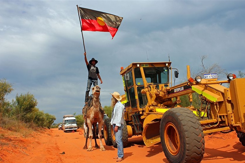 Un homme sur un chameau agitant un drapeau.