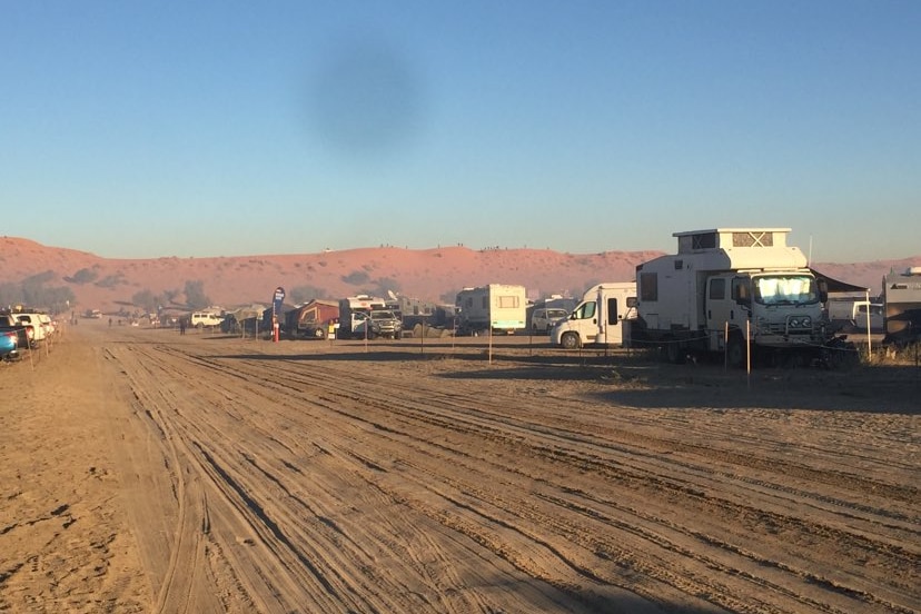 A dusty road with caravans parked.