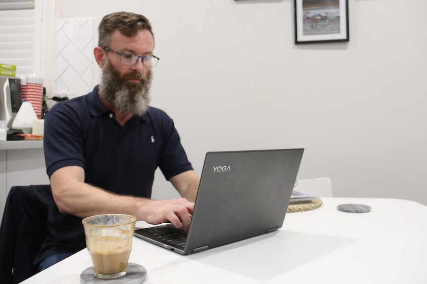 Data analyst Timothy Morgan using a computer in an office