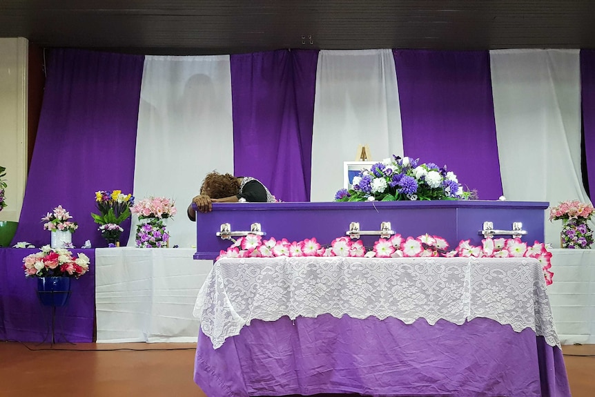 A woman breaks down on Alexsandra Hall's coffin at her funeral in January 2018.