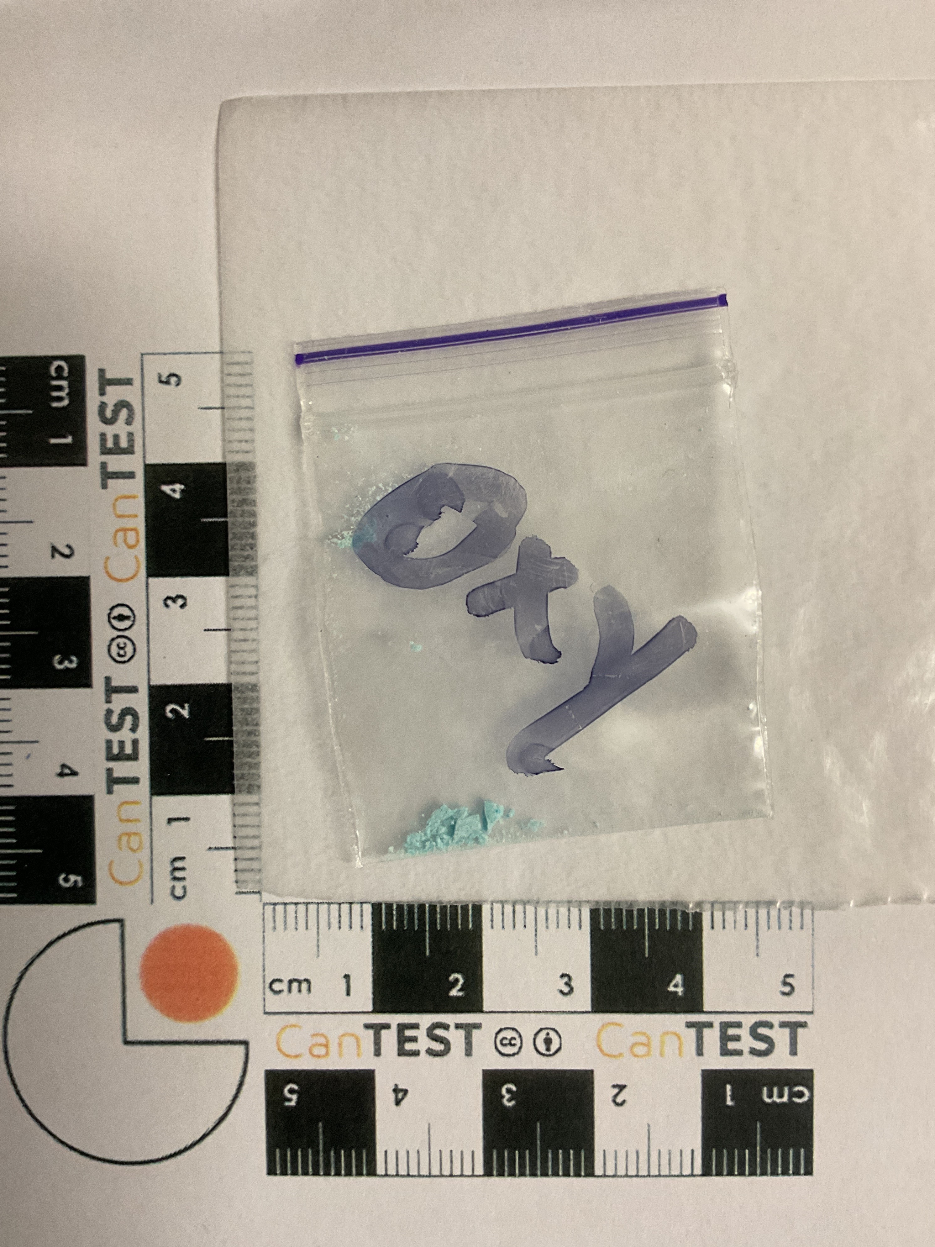A photo of a crushed blue powder in a small clear bag next to a measuring ruler.