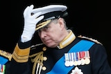 Prince Andrew touches his military hat and looks at the camera.