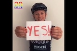 Cyclist Annette Edmondson holds a sign saying the word "yes".
